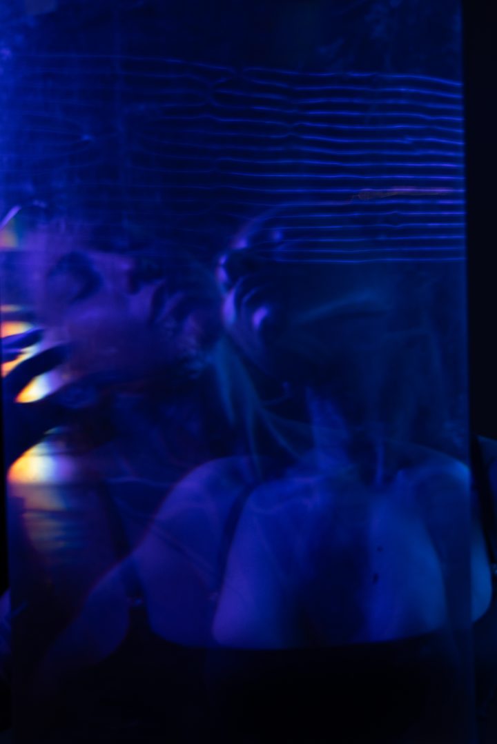 A figure dissolved into green by long-exposure motion, a raised hand the only fixed point in the wash of color.