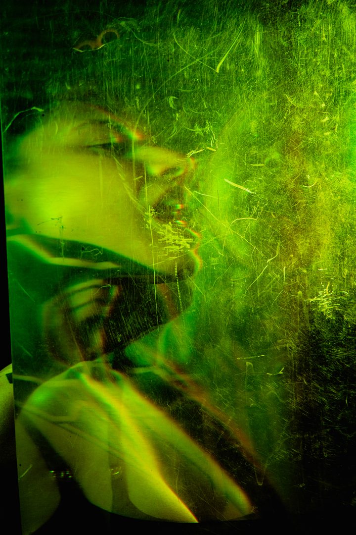A figure under a projected grid of light in cool blue, the highlights mapping across the body and the dark ground.